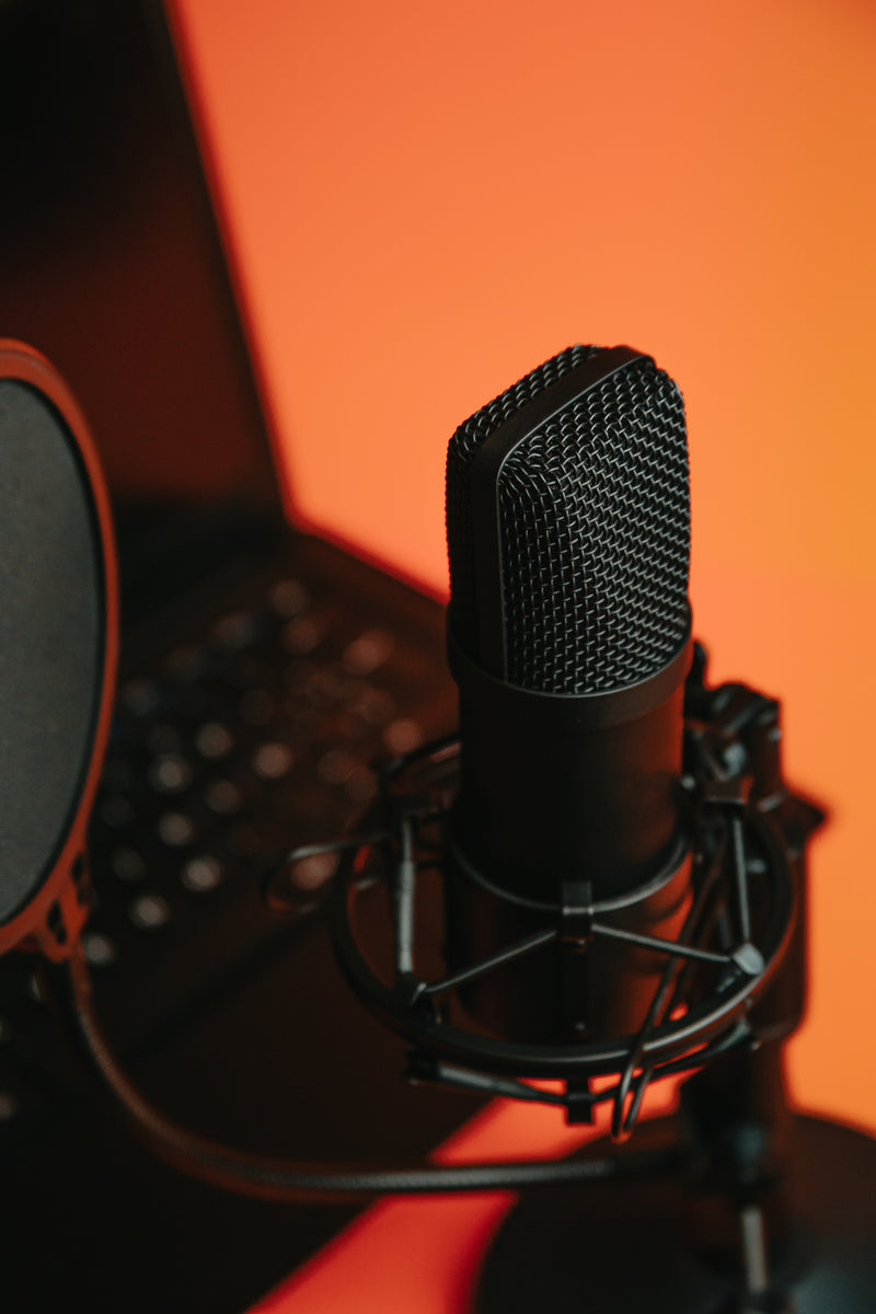 Black microphone on a stand reflecting orange light background